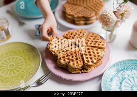 Ragazzo che raccoglie i waffle freschi dal piatto Foto Stock