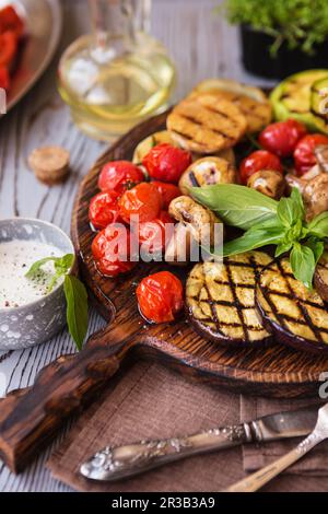 Verdure grigliate sul tagliere su fondo di legno. Verdure alla griglia (peperone colorato, Foto Stock