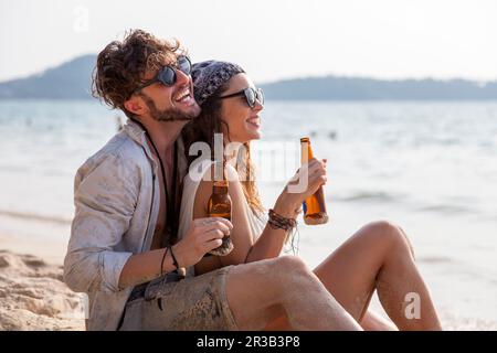 Coppia felice che beve birra in spiaggia Foto Stock