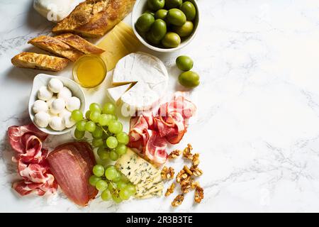 Piatto di formaggi con brie, parmigiano, cheddar e carne, frutta e baguette Foto Stock