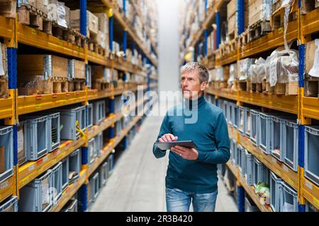 Uomo d'affari che prende inventario tenendo il tablet PC in magazzino Foto Stock