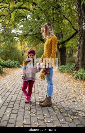 Figlia sorridente che tiene la mano della madre sul sentiero Foto Stock