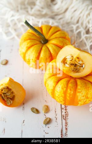 Composizione di vita morta con mini zucche decorative colorate e semi di zucca. Mini zucca arancione Foto Stock