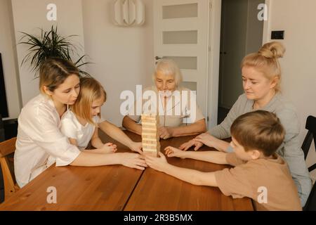 Gioco di famiglia multi-generazione sul tavolo a casa Foto Stock