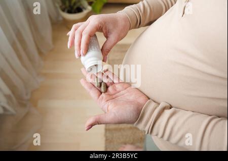 Donna incinta che prende pillole di vitamina a casa Foto Stock