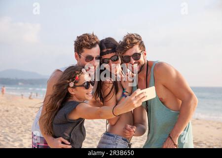 Felice donna che prende selfie con gli amici in vacanza in spiaggia Foto Stock