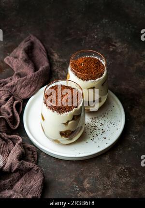 Tiramisù dessert aromatizzato al caffè raggizionale servito in una tazza di vetro sul tavolo Foto Stock