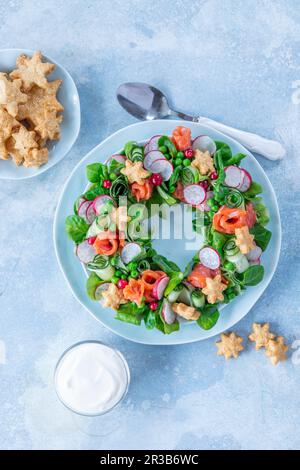 Insalata sotto forma di corona con salmone, cetriolo, ravanello, piselli, mais e formaggio biscotti stelle Foto Stock