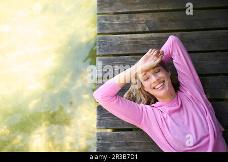 Donna matura e felice sdraiata sul lungomare Foto Stock