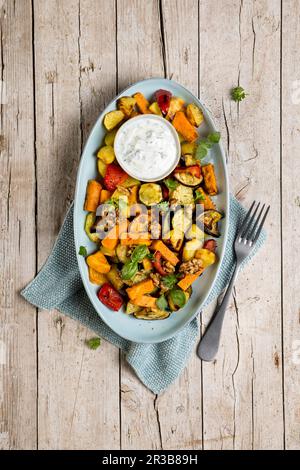 Verdure al forno con yogurt alle erbe e noci caramellate Foto Stock