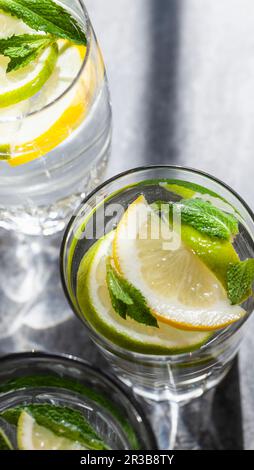 Vari bicchieri d'acqua ripieni di limoni, lime, menta e zenzero Foto Stock