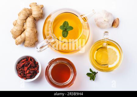 Zenzero fatto in casa e tè al limone, miele, goji, aglio, sfondo bianco Foto Stock