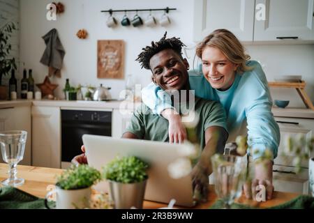 Giovane coppia che guarda il computer portatile in cucina a casa Foto Stock