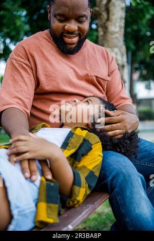 Sorridente padre con figlia sdraiata in giro al parco Foto Stock