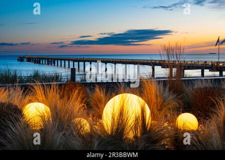 Germania, Mecklenburg-Vorpommern, Binz, sfere illuminanti sulla spiaggia dell'isola di Rugen con il molo Seebrucke Binz sullo sfondo Foto Stock