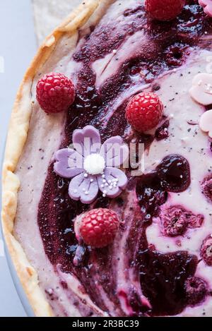 Cheesecake vegana con frutti di bosco e fiori di marzapane Foto Stock