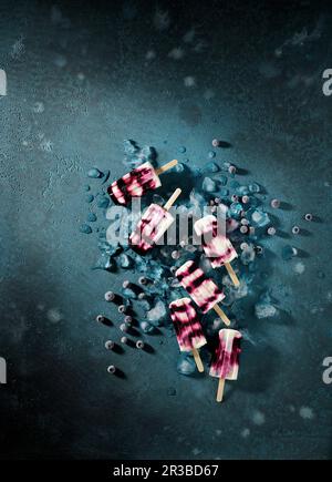 Papicles di yogurt ai mirtilli su una superficie scura Foto Stock