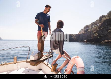 Uomo e donna a prua in barca a vela in mare Foto Stock