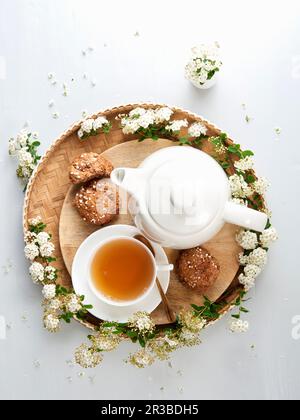 Teacup, teiera, biscotti e fiori bianchi Foto Stock