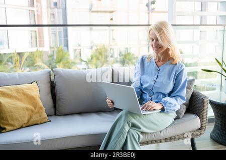 Donna freelance che lavora su un computer portatile sul balcone Foto Stock
