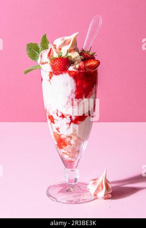 Sundae di fragole con gelato, panna montata, meringa tritata, salsa di fragole e menta Foto Stock