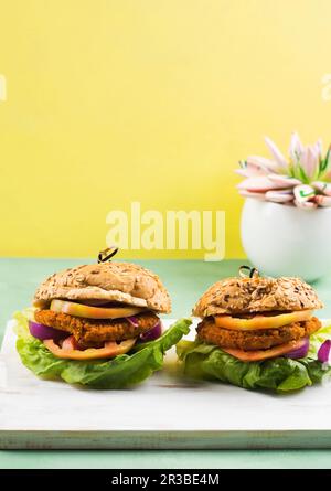 Hamburger vegano a base di farro e tortino di soia e verdure con insalata di lattuga, pomodoro e cipolla rossa Foto Stock