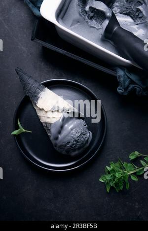 Gelato nero in un cono bicolore Foto Stock