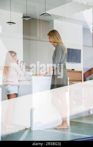 Madre e figlia preparano il cibo visto attraverso la finestra di vetro Foto Stock