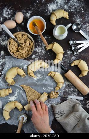 Preparazione di croissant con semi di papavero bianco e mandorle Foto Stock
