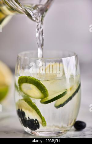 Versare acqua fresca fredda infusa in un bicchiere Foto Stock