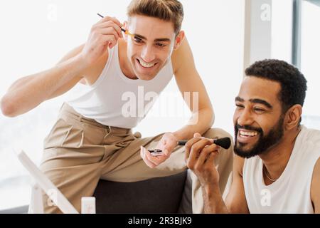 Amici felici che applicano il make-up con pennello Foto Stock