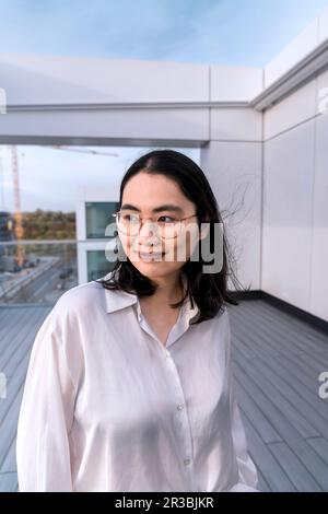 Giovane donna d'affari premurosa in camicia bianca sulla terrazza dell'edificio degli uffici Foto Stock
