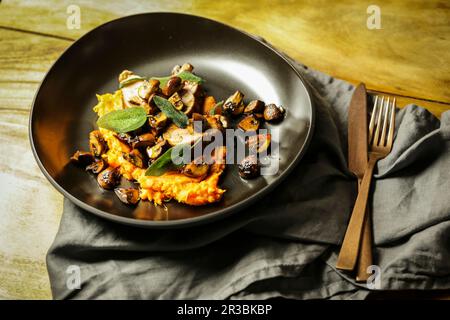 Filetto di maiale con funghi e salvia fritta su un letto di purè di patate dolci Foto Stock