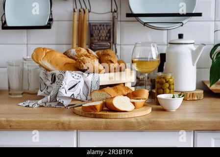 Varietà di pane con formaggio cremoso, olive e vino bianco Foto Stock