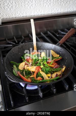 Friggete le verdure nella padella mentre mescolate Foto Stock