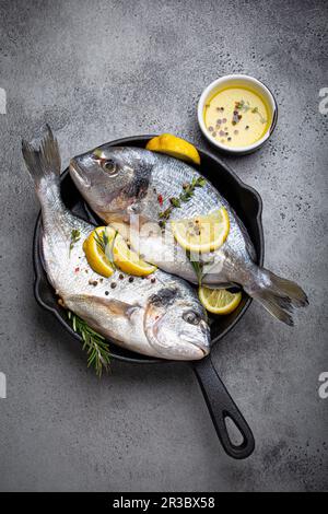 Orata di mare cruda con limone, erbe aromatiche e spezie in padella Foto Stock