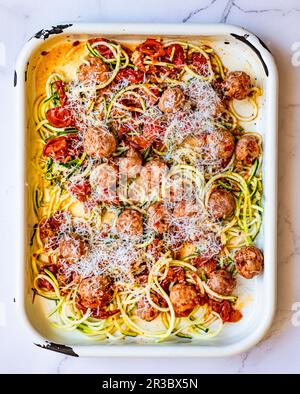 Polpette di maiale Traybake con pomodori arrosto e tagliatelle di zucchine Foto Stock