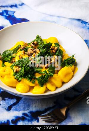 Ciotola di gnocchi in salsa di zucca con kale e noci Foto Stock