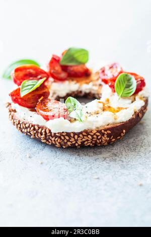 Bagnello per la colazione con feta e pomodori stufati Foto Stock