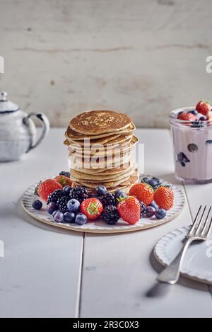 Una pila di pancake con frutti di bosco freschi e yogurt alla fragola Foto Stock