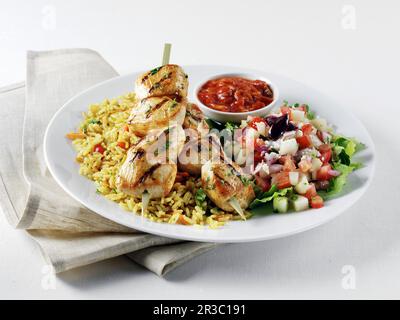 Kabobs di pollo su riso giallo mediterraneo, insalata greca e salsa Harrisa Foto Stock