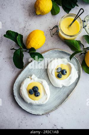 Cagliata di limone in nidi meringa con mirtilli Foto Stock