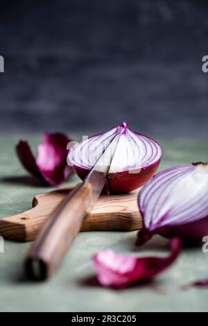 Cipolle rosse con un coltello su un tagliere Foto Stock