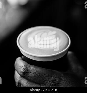 Barista africano del caffè che tiene una tazza di take away Foto Stock