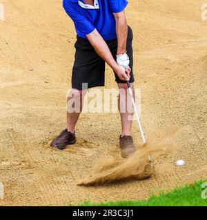 Uomo che colpisce la sfera di golf da un bunker Foto Stock