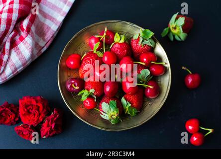 Ciliegie e fragole su un piatto d'oro Foto Stock