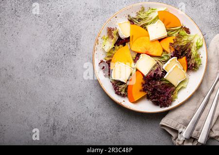 Insalata di persimmon con formaggio brie e foglie fresche di insalata Foto Stock