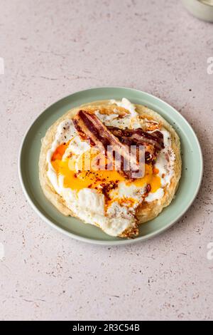 Paratha con yogurt all'aglio, uova fritte, pancetta e olio di peperoncino Foto Stock