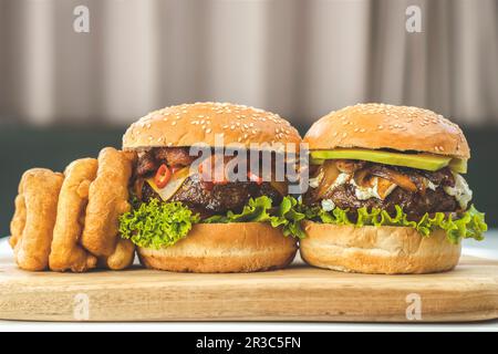 Hamburger di formaggio con peperoncino, pancetta, anelli di cipolla e hamburger con avocado, feta, cipolle caramellate Foto Stock