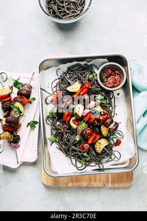 Spaghetti di fagioli neri con spiedini di verdure Foto Stock